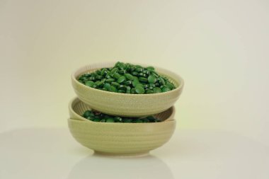 Spirulina algae .Super food. Spirulina pills in a round green cups set on a light background with reflection.Vitamins and dietary supplements.Food supplements for a healthy lifestyle