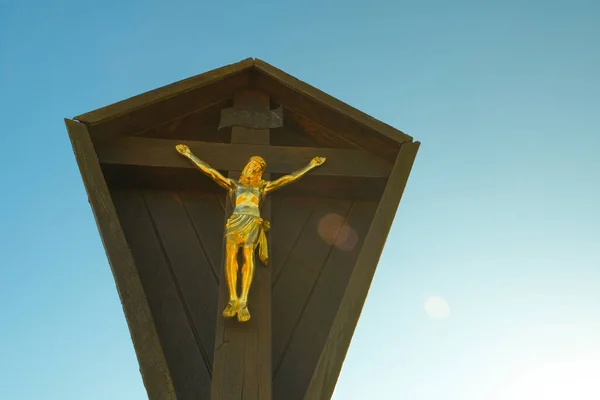 Jesus Christ on the wood cross on the blue sky with the rays of the sun. Christian and catholic faith symbol.