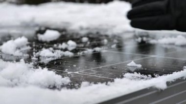 Kışın güneş paneli. Eldivenler güneş panellerinden kar temizliyor. Güneş panellerini kardan temizliyor. Kışın güneş panelleriyle elektrik alıyoruz. 4k görüntü