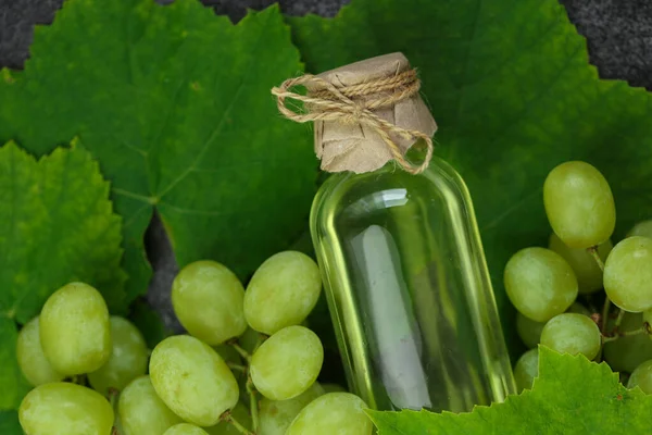 Grape oil.grape vinegar.Oil in a transparent bottle and grapes with leaves .organic oils.Base cosmetic oil for massage and care for face and body.