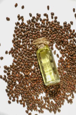 Pine nuts oil.shelled pine nuts and a bottle of cedar oil.glass bottle with yellow oil lies on a white background.Organic natural bio nut oil.