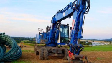 Construction machinery for pipe laying. Water pipes and construction installation equipment in the field. Carrying out water construction work.Plumbing installation.Pipe laying.Blue excavator with