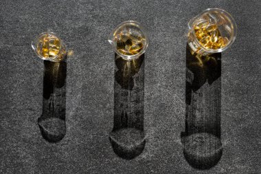 Fish oil capsules in transparent laboratory flasks on a black slate background in bright hard light with shadows.Cod Liver Oil. Omega-3.omega fatty acids.Natural supplements and vitamin. 