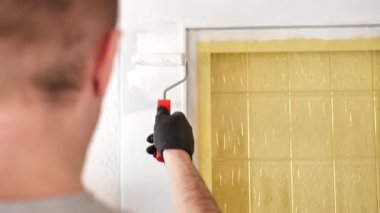 Redecorating.Door painting.A man paints a wooden door white with a roller.Home renovation inside.Construction roller for painting.Painting wooden surfaces. Construction and renovation concept.