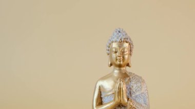 Buddha golden statue on beige background.Meditation and relaxation symbol.Buddhism religion background.Calm, balance and harmony. High quality 4k footage