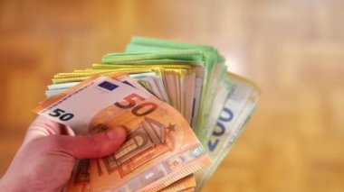 pack of money in a close -up hand.large pack of euro bills on brown background. 4k footage