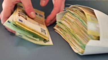 Zarfın içinde para. Eller banknotları yeniden hesaplar ve gri bir arkaplan üzerine bir zarf koyun. Düşük önerge. Avrupa ülkelerindeki giderler ve gelirler. 4k görüntü