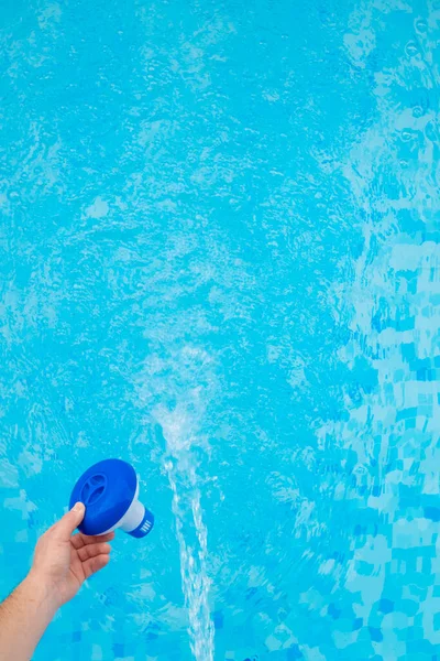 プールフィルター 手はプールの青い水に洗浄フィルターを投げます 青い水フィルタースイミングプールのクリーニング — ストック写真