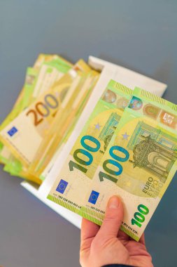 Avro banknotları bir zarfın içinde. Avro banknotları gri arka planda beyaz bir konteynırın içinde. Paranın yeniden hesaplanması. Avrupa ülkelerindeki harcamalar ve gelirler