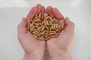 Guarana kapsülleri beyaz arka planda erkeklerin elinde. guarana tozlu kapsüller. Alternatif tıp ve homeopati. Üretim ve vitaminler. Doğal Enerji Biostimülatörü.