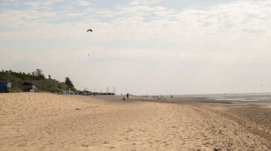 Deniz eğlencesi ve tatil. Wadden Denizi. Sahilde ufuktaki insanların siluetleri. Deniz kıyısında uçurtma uçurmak. Yaz havası. 