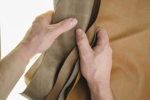 本革の品揃え本革の本物の部分は白い背景に男性の手で設定します 茶色の革の背景 — ストック写真