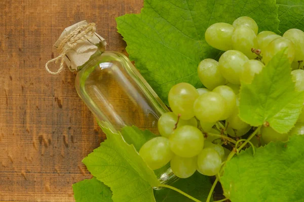 Traubenöl Auf Hölzernem Hintergrund Ölflasche Und Bund Grüner Trauben Kosmetisches — Stockfoto
