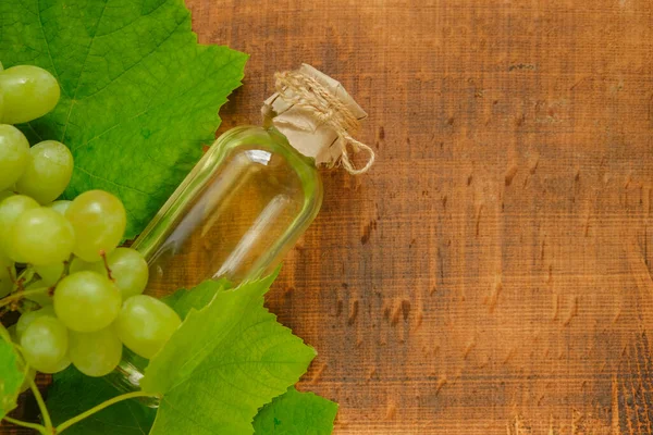 Traubenöl Auf Hölzernem Hintergrund Ölflasche Und Bund Grüner Trauben Auf — Stockfoto