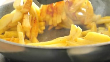 Kızarmış patatesler. Kızarmış patatesleri yakın plan kahverengi çıtır çıtır ile iştah açıyorlar. Siyah spatula patatesleri pantalonda çeviriyor. Yüksek kalite 4k görüntü