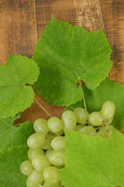 Tahta masa yapraklı yeşil üzümler. Organik doğal meyve ve böğürtlen. Bir demet üzüm.