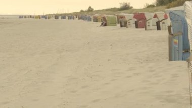 Deniz kıyısındaki sahil kulübesi. Wadden Deniz Kıyısı. Denizde dinlen. Plaj hasır kutuları beyaz kuma kurulmuş. Fer Adası. Almanya. Kuzey Denizi. 4k görüntü