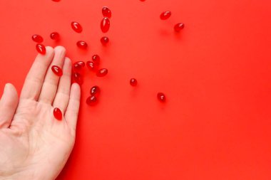 Krill yağ kapsülleri. Omega yağ asitleri. Kırmızı arka planda uçan jelatin kırmızı kril yağ kapsülleri. Doğal takviyeler 