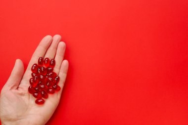 Krill yağ kapsülleri .omega yağ asitleri. Bir kadının elinde kırmızı arka planda jelatin kırmızı kril yağ kapsülleri. Doğal takviyeler 