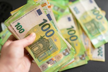 100 avroluk banknotlar el ele. Avrupa Birliği parası. Avro Bölgesi 'nde kazanç ve harcamalar, Avrupa' da alarm, sosyal yardım ve emekli aylıkları.
