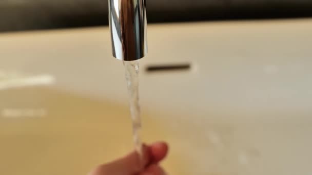 洗手间的洗手过程 清洁卫生的概念 穿着棕色运动衫的女孩在流动的水中在白色的鼻窦上洗手 — 图库视频影像