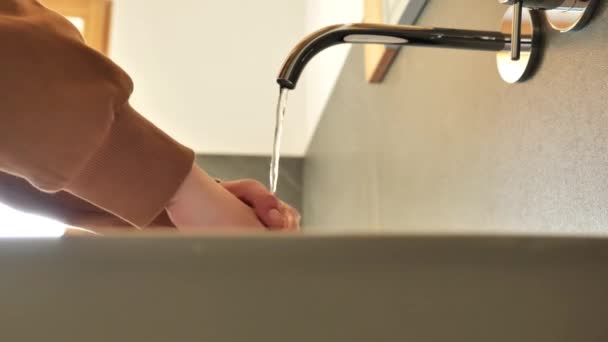 清洁卫生的概念 在厕所里 穿着棕色运动衫的女孩在自来水下洗手 慢动作高质量的4K镜头 — 图库视频影像
