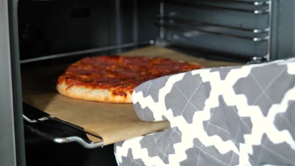 ピザ作り オーブンからピザを食欲をそそるミトンの手はオーブンのクローズアップからホットピザを取ります 4K映像 — ストック動画