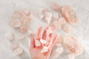  Avuç içinin içindeki kuvars parçaları. Değerli değerli taş. Gri mermer zeminde gül kuvars üzerine doğal taş. Pembe tılsım taşı.