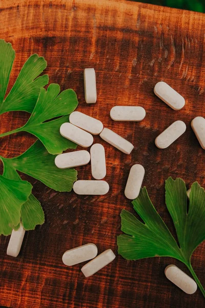 Liść Miłorzębu Japońskiego Białe Tabletki Drewnianym Brązowym Tle Planszy Medycyna — Zdjęcie stockowe