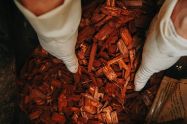Bahçedeki toprağı çimdikliyorum. Eller çantadan kahverengi odun parçaları topluyor. Ellerinde kahverengi odun parçaları. Bahçe için dekoratif cipsler..