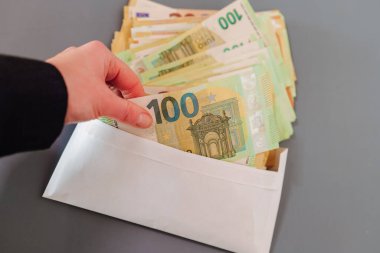 Zarfın içinde para. Maaş zarfın içinde. Avro banknotları bir zarfın içinde. Kadınların elleri, gri bir arkaplanda yakın plan bir zarfta Euro banknotlarını düzenliyor. Elleri banknotları yeniden hesaplıyor ve...