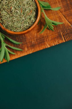 Stevia rebaudiana yuvarlak kâselerde kuru yapraklar ve koyu yeşil arka planda tahta üzerinde taze bitki dalları. Tatlı yaprak şekeri yerine. Diyet gıda tatlandırıcı. Tatlı bitki..