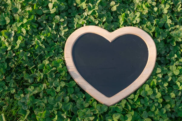 Earth Day.Love for nature. clover background and heart blank board.Ecological concept.st patricks day background.Heart chalk board blank in green clover.
