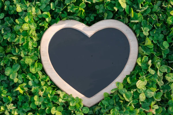 Earth Day.Love for nature. Green clover background and heart blank board.Ecological concept.st patricks day background.Heart chalk board blank in green clover.