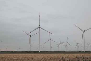 Rüzgâr değirmenleri sisli ve bulutlu bir havada bir tarlaya kurulur. Yeşil Enerji Kaynağı. Alternatif enerji kaynakları. Çevre dostu doğal enerji kaynağı.. 