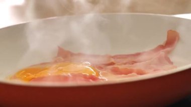 Yumurtalar kızartma tavasına pastırmayla birlikte kızarmış panoya düşer. Yumurtalı domuz yağı. Çırpılmış yumurta. Pastırmalı sahanda yumurta. 4k görüntü