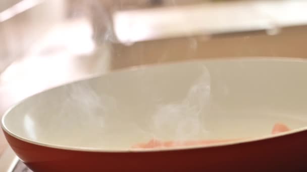 スモーキーな揚げベーコン 太陽の下でフライパンにベーコンのストリップを置く手 朝食の準備 4K映像 — ストック動画