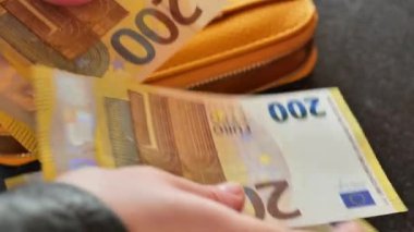 Para dolu cüzdan. El, cüzdandan 200 Euro 'luk banknotları yakın plan çeker. 4k görüntü