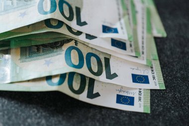 Yüz avroluk özgeçmiş. Avro parası. Avro banknotları siyah bir masaya istiflenmiş. Yumuşak odaklanma. Avrupa Birliği parası. Avro Bölgesi 'nde kazanç ve harcamalar. Avrupa 'da maaş, yardım ve emekli aylıkları.