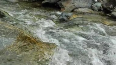 Dağ nehri ve düşen kar. Damlalar ve sıçramalarla dolu fırtınalı su akıntısı. Dağlarda karlı bir bahar. bir dağ nehrinin akan akıntısı. 4k görüntü