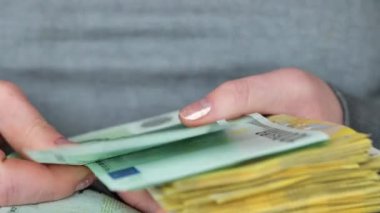 Avro paketine yakın çekim. Banknotları saymak. Avrupa Birliği 'nde kadın maaşları. Kadın ticareti ve kâr. Eller 100 Euro 'luk banknotları yakından sayıyor. 4k görüntü