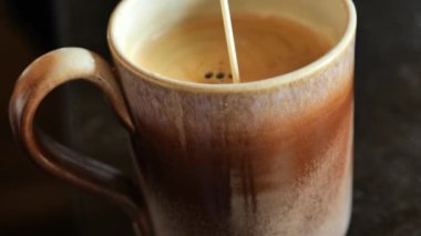 Kahve fincanı ve siyah masa kreması. Kremalı jet sade kahve bardağına dökülüyor. Sabah kahvesi. Sabah içkisi. 4k görüntü