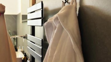 Kurutulmuş havlular. Havlu değişimi. Havlu ve ısıtmalı havlu. Banyodaki ısıtılmış havlunun üzerinde bej ve gri kabarık havlu. Düzen ve temizlik kavramı. 