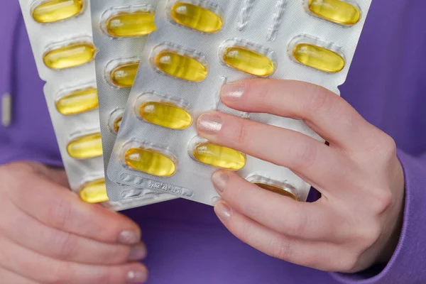 Omega fatty acids in jelly capsules.Dietary supplements and vitamins in womens nutrition.Fish oil capsules in blisters in hands .
