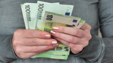 Avro parası. Kadın eli para sayar. Avrupa Birliği 'nde kadın maaşı. 100 Euro 'luk banknotlar kadınların elinde, yakın plan. Kadın işi ve kâr. 4k görüntü