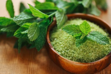 Nane şekerli tuz. Vegan doğal vücut kozmetiği. Yuvarlak ahşap bir kasede yeşil deniz tuzu.