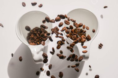 Kahve. Beyaz seramik fincanlar ve düşen kahve çekirdekleri. Beyaz bardakta kahve. Geleneksel sabah içkisi.. 