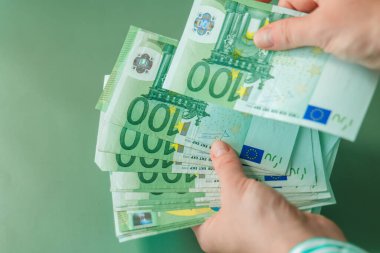 100 avroluk banknotlar yeşil bir zemine güveniyordu. Yeşil bir yeşil gömleğin içinde avroluk para tutuyordu. Avrupa Birliği parası. Avro bölgesinde kazançlar ve harcamalar.. 