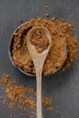 Siyah arka planda, tahta bir kaşıkta, yuvarlak bir bardakta Guarana tozu. Doğal tonik. Alternatif tıp ve homeopati. Bağış ve vitaminler. Sağlıklı beslenme. Spor beslenmesi. 