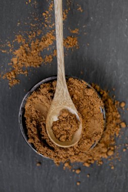 Guarana kahverengi tozu, tahta kaşıkta yuvarlak bir fincanda, arka planda. Doğal tonik. Alternatif tıp ve homeopati. Bağış ve vitaminler. Sağlıklı beslenme. Spor beslenmesi. 